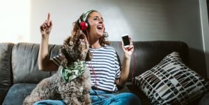 Lovely brown dog singing with her owner at home, sitting on the sofa. Funny time together.