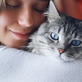 Woman at home in light room holding and hug her lovely fluffy cat